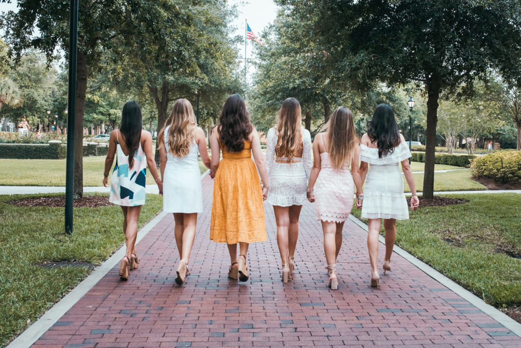 グリーンの中颯爽と歩くワンピースをきた6人の女性の後ろ姿の写真