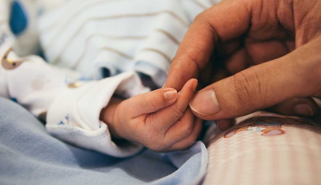 新生児と手を繋ぐ親の指